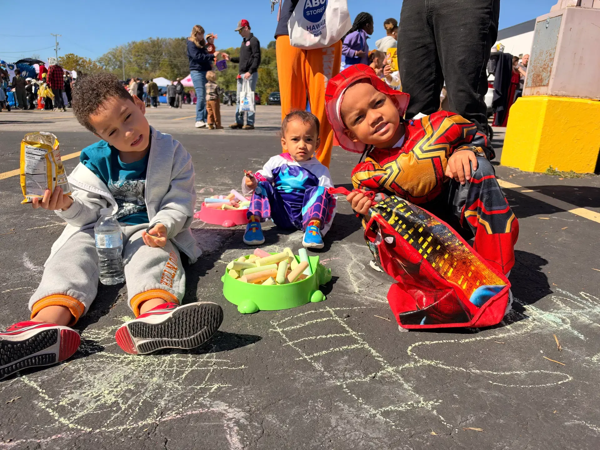 A child in a red-and-gold superhero costume enjoys a festival snack.