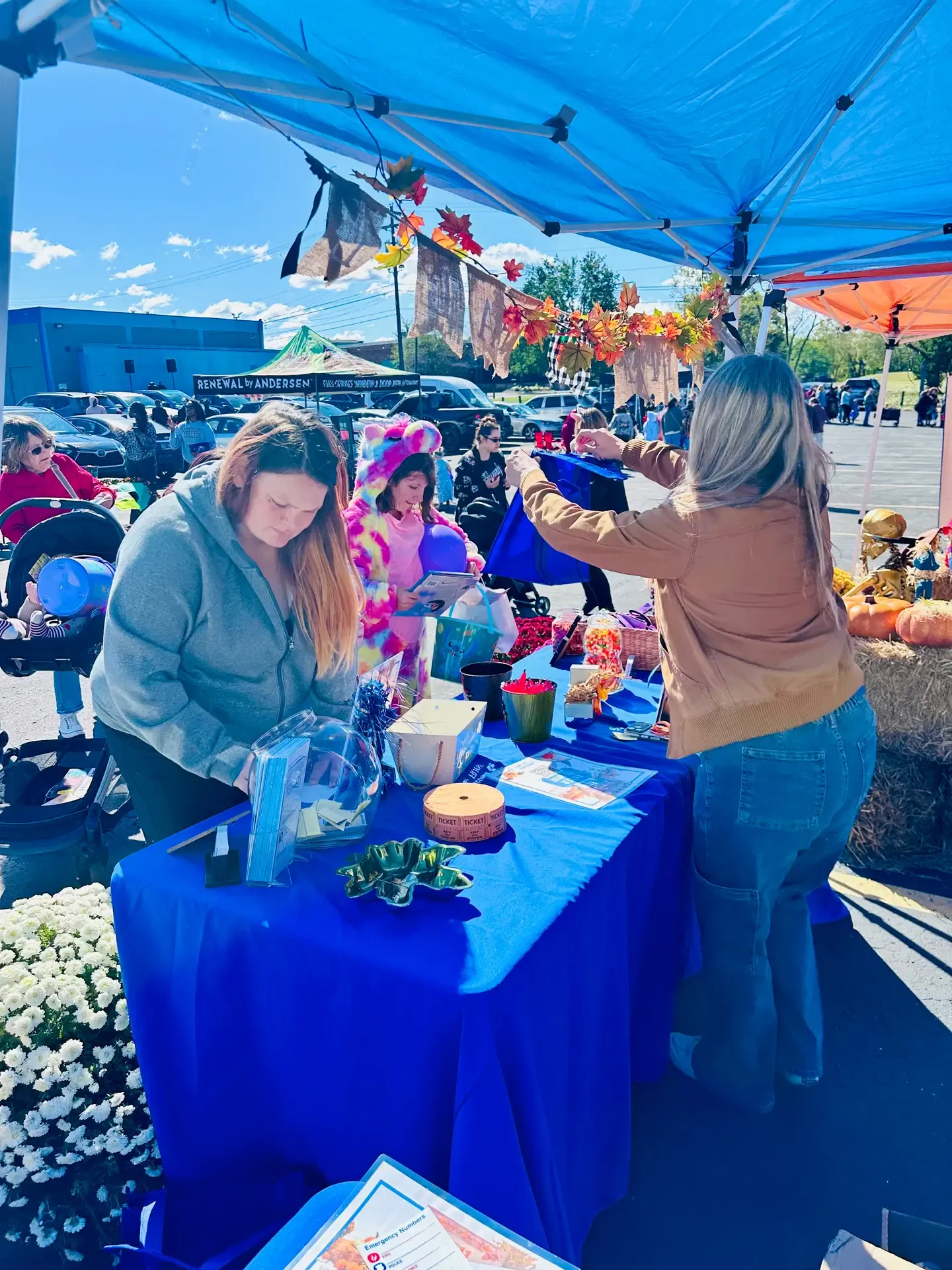 A vendor welcomes a visitor at the festival information table.
