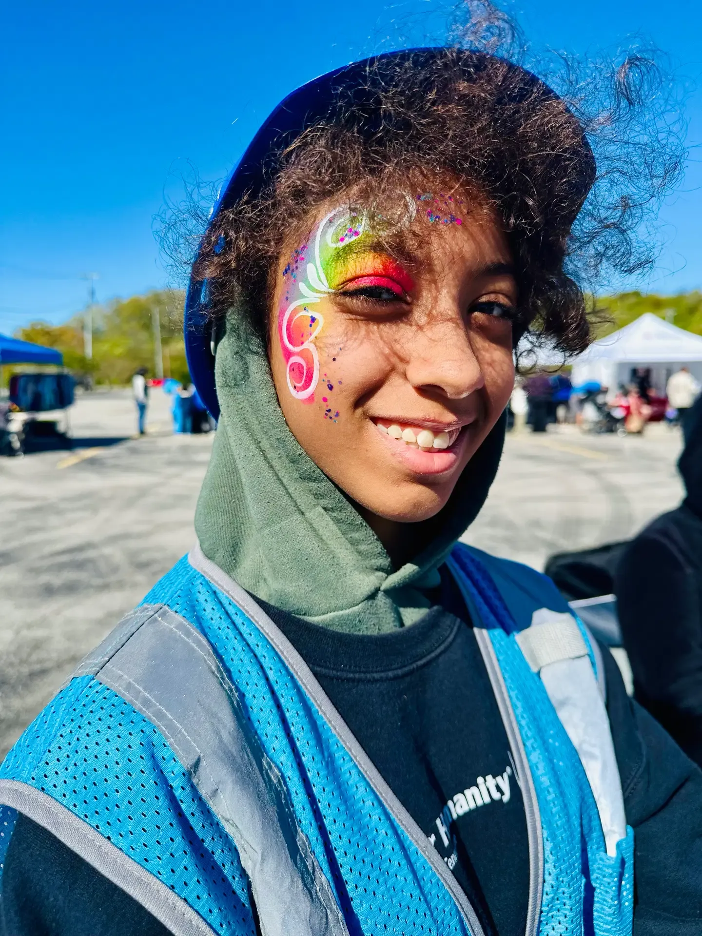 A young festival guest shows colorful face paint.