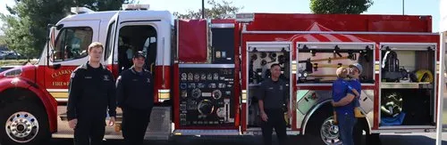 Firefighters and children beside a fire truck at the Fall Safety Festival