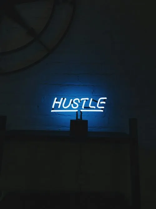 Blue neon sign reading Hustle